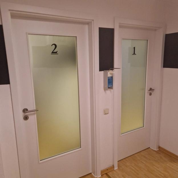 Praxis Türen Nummeriert Zwei weiße Praxistüren mit Glaseinsatz und schwarzer Nummerierung für Räume.