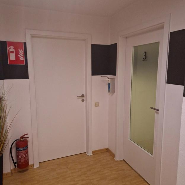 Praxis Türen Raumaufteilung Moderne Praxistüren mit Glas und Raumkennzeichnung, daneben Feuerlöscher im Flur.