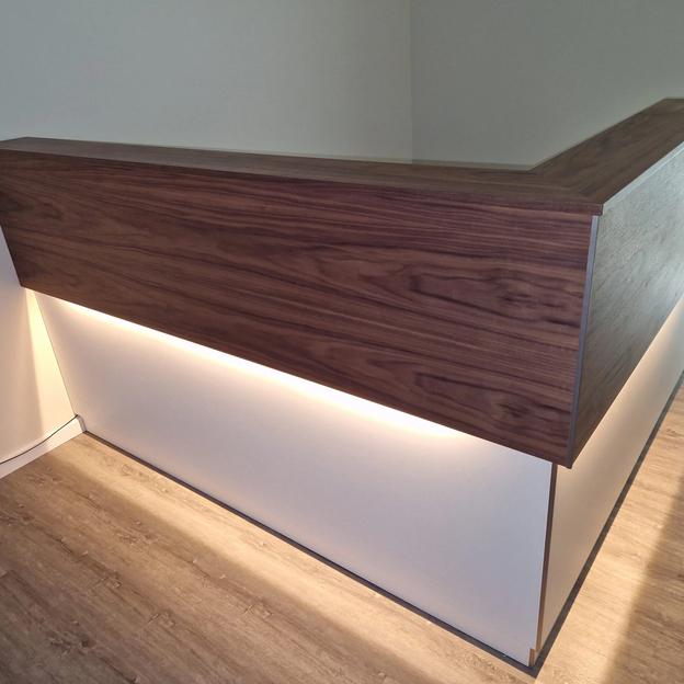 Empfangstheke Holz Weiß LED Moderne Empfangstheke mit Holzfront, weißem Unterbau und integrierter LED-Beleuchtung.