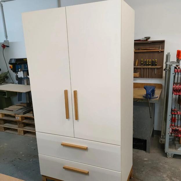 Moderner Schrank Werkstattbau Weißer Schrank mit Holzgriffen und zwei Schubladen, gefertigt in einer Werkstatt.