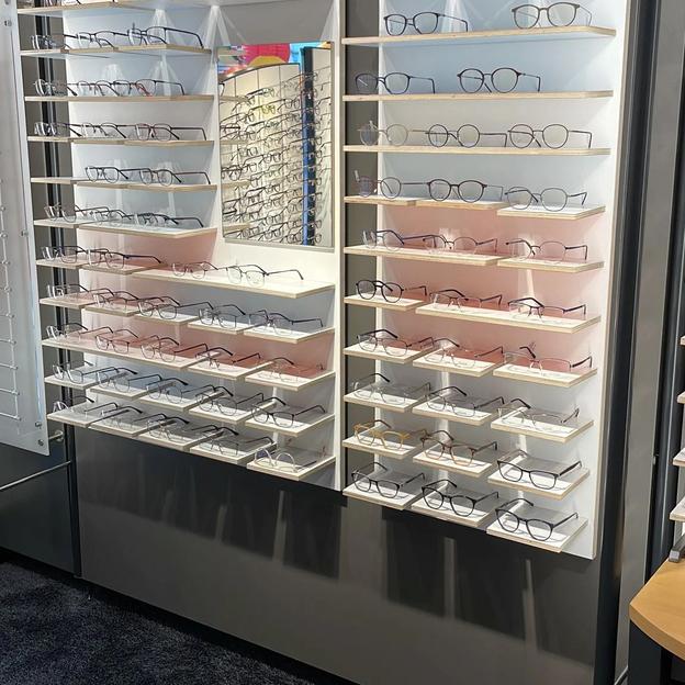 Brillenwand Ladenbau Optiker Große Brillenwand mit vielen Brillengestellen, modern gestaltet für Optikgeschäft.