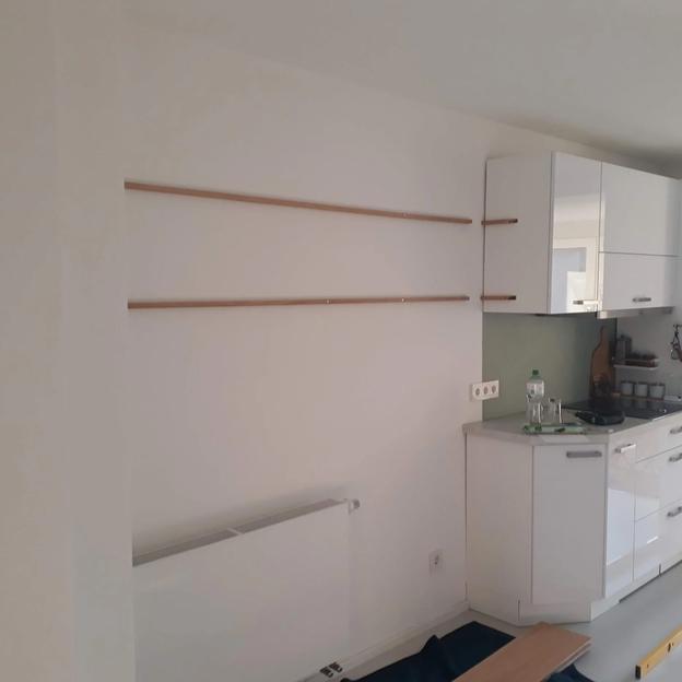 Küchenregale Wandmontage Holz Lange Wandregale aus Holz in einer hellen Küche neben weißen Hängeschränken montiert.